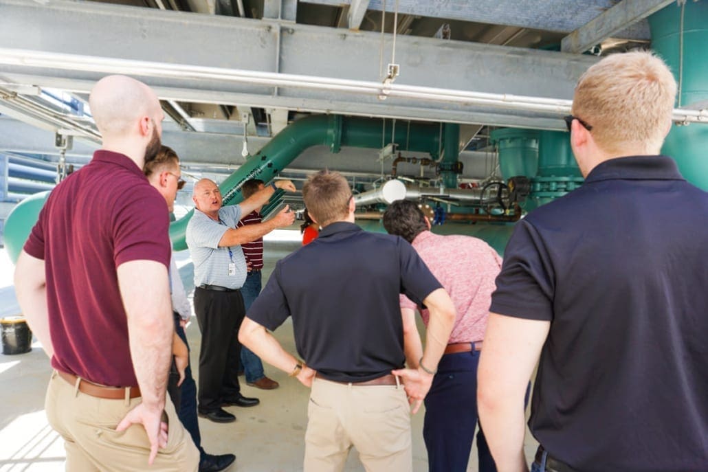 Principal from RWB Consulting Engineers stands beneath cooling tower to show group of young engineers the mechanical design